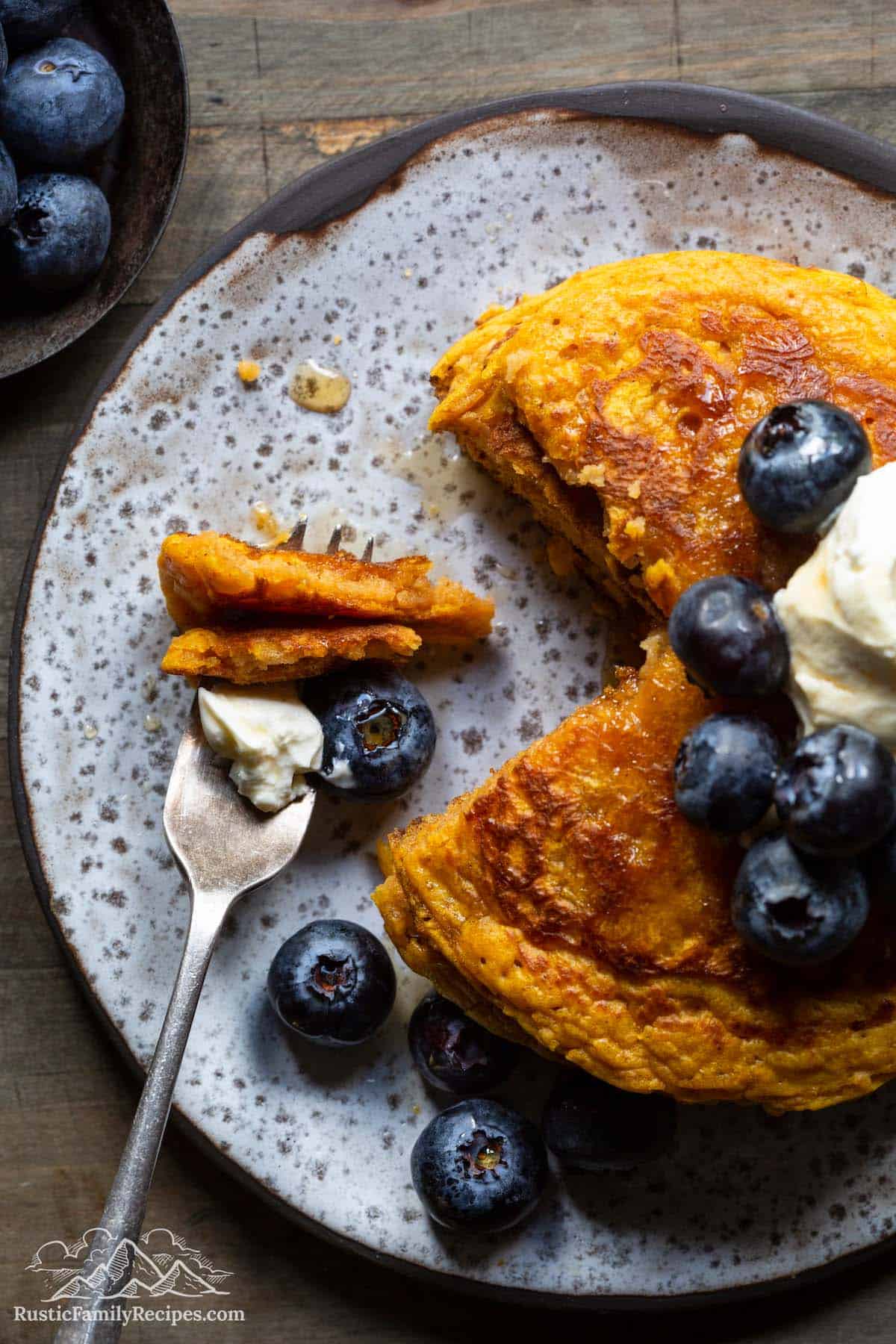 Pumpkin pancakes on a plate, top view with a fork that has a mouthful of pancakes on it
