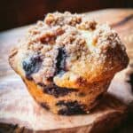 A blueberry coffee cake muffin on a wooden board