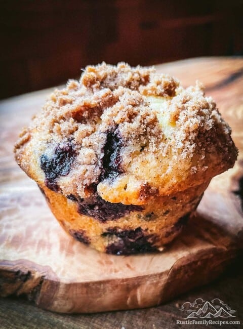 A blueberry coffee cake muffin on a wooden board