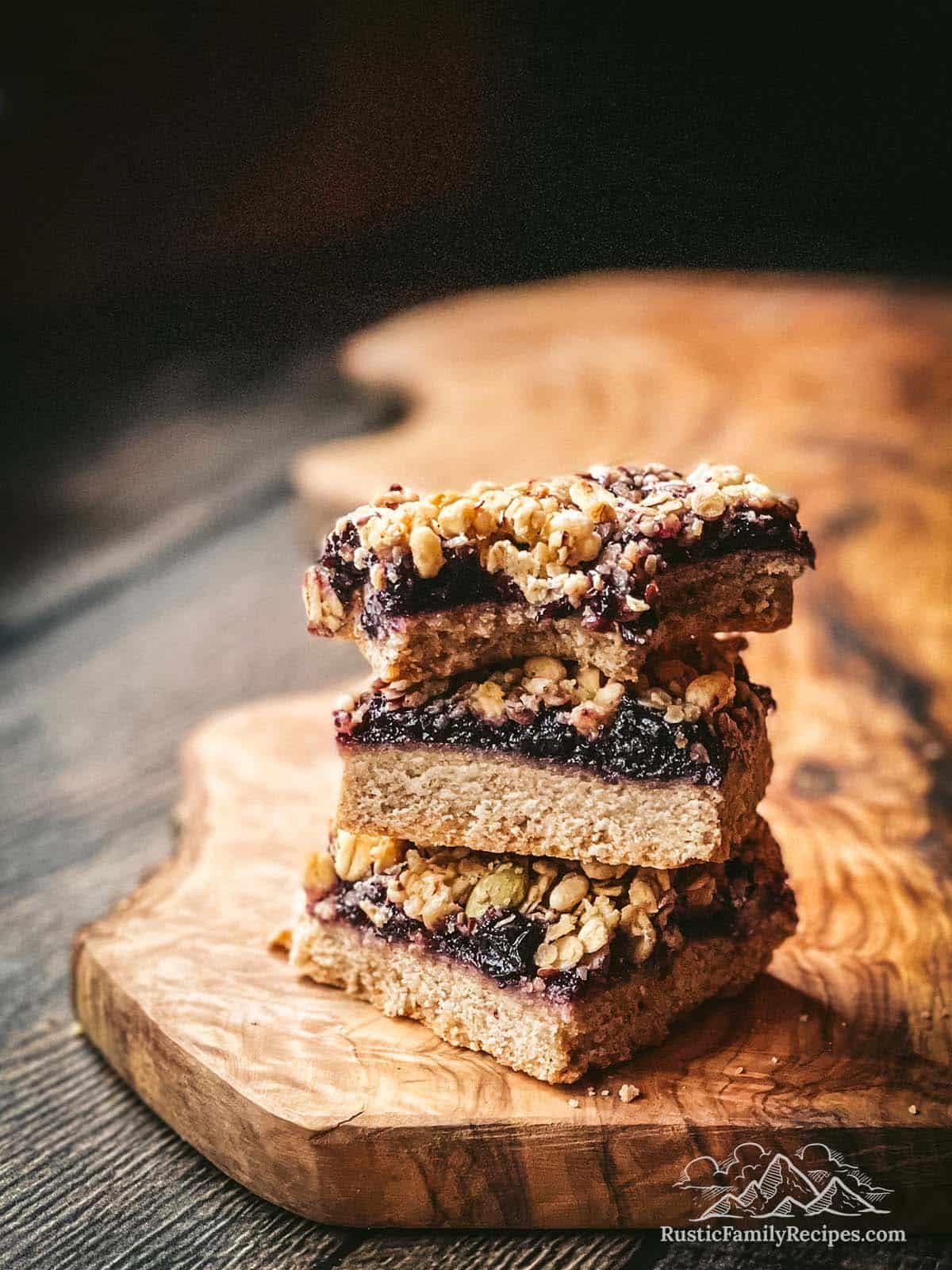 3 walnut blueberry shortbread cookie bars stacked on top of each other, a bite taken out of one.