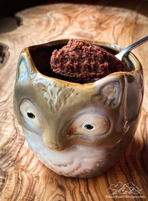 A brownie made in a fox shaped mug with a spoon scooping a bite out.