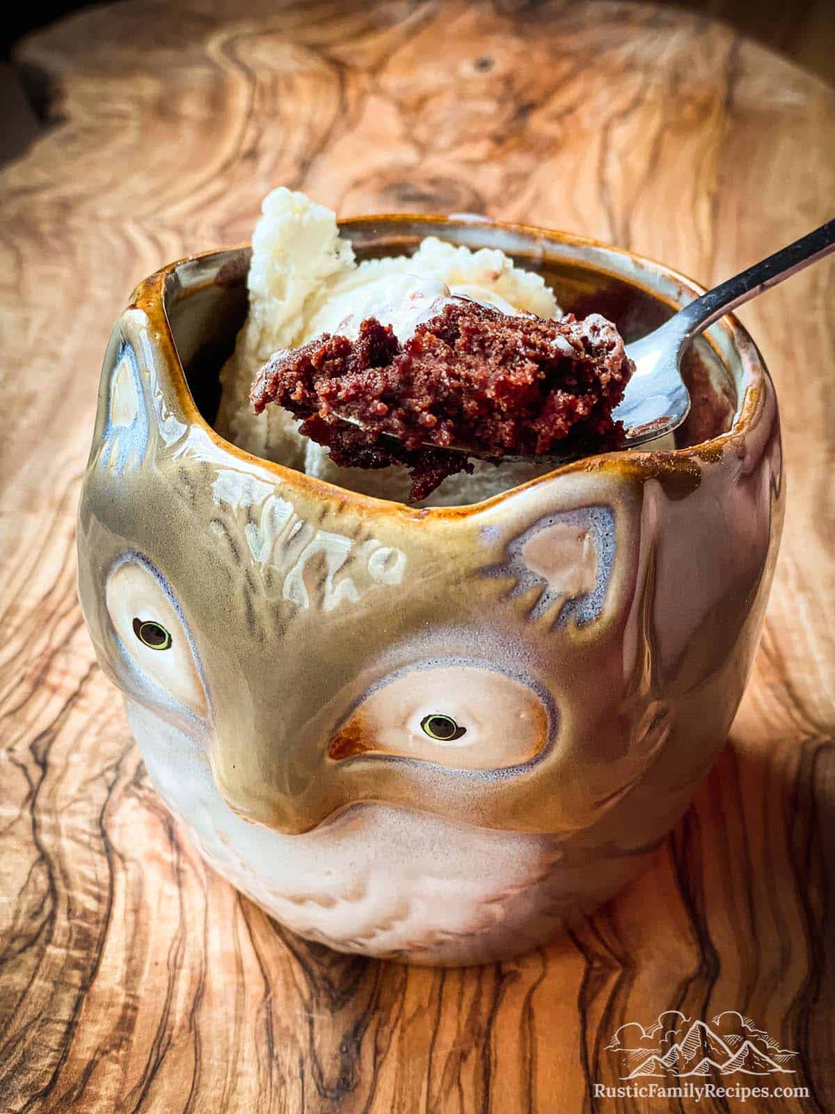 Brownie in a fox shaped mug with ice cream and a spoon scooping some out.