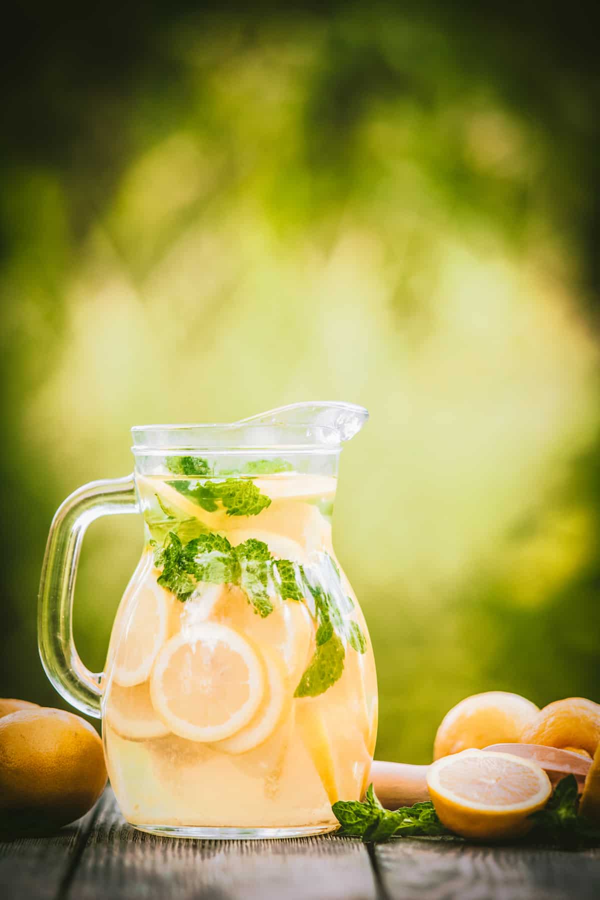 Homemade lemonade in a pitcher next to lemons and a juicer