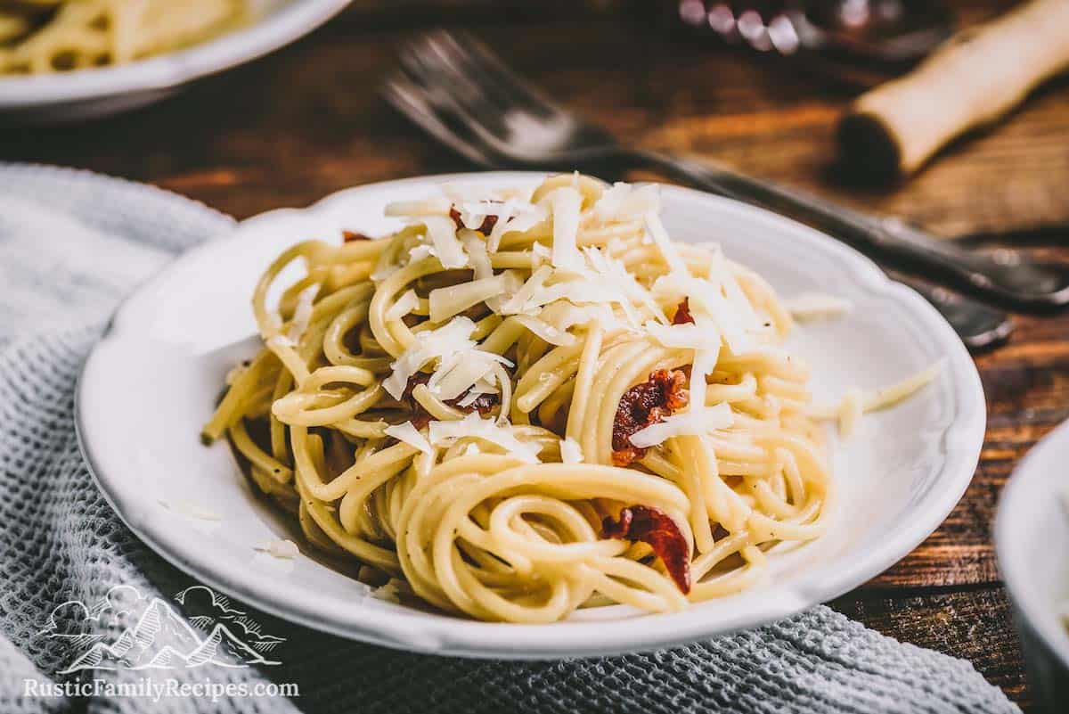 A white plate with pasta carbonara on a wood table