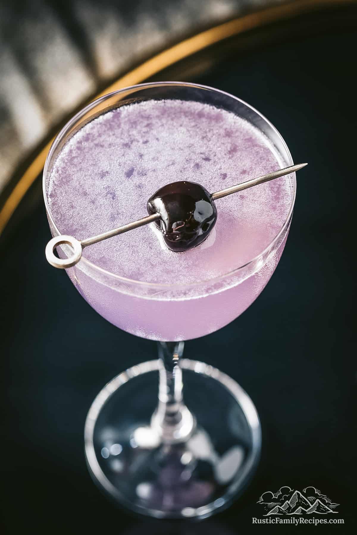 Purple Aviation cocktail in a glass topped with a cherry