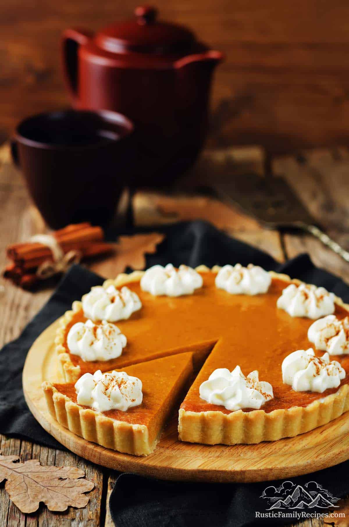 Pumpkin tart with a slice cut and dollops of whipped cream
