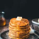 Stack of pumpkin johnnycakes with butter and syrup