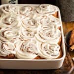 A white baking dish with frosted homemade cinnamon buns