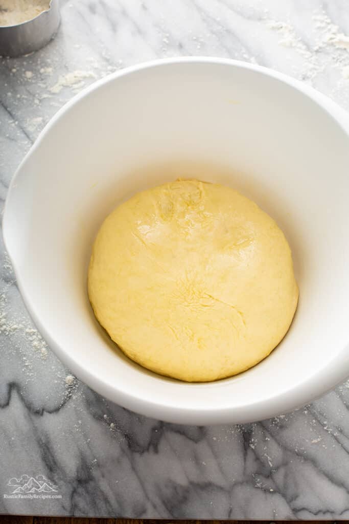 A white bowl with cinnamon bun dough in it