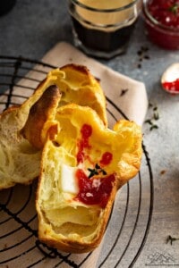 A cut open popover with melting butter and jam