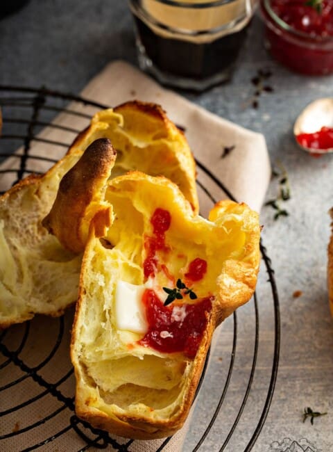 A cut open popover with melting butter and jam