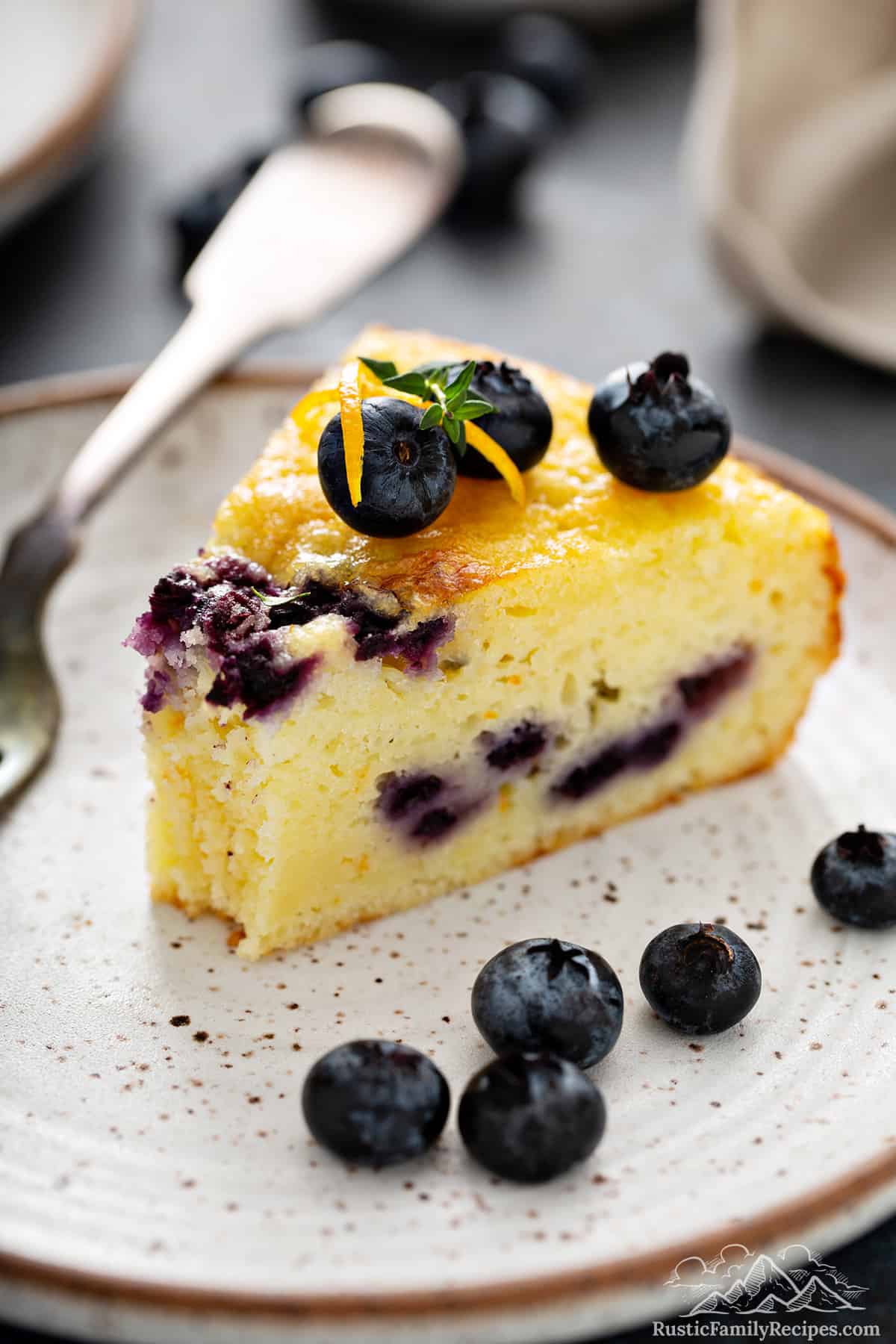 A slice of blueberry coffee cake with a bite taken out and blueberries on top.