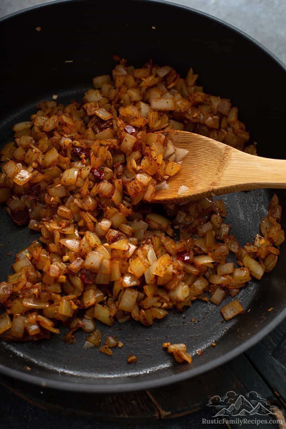 A pan with caramelized onions and a wooden spoon.