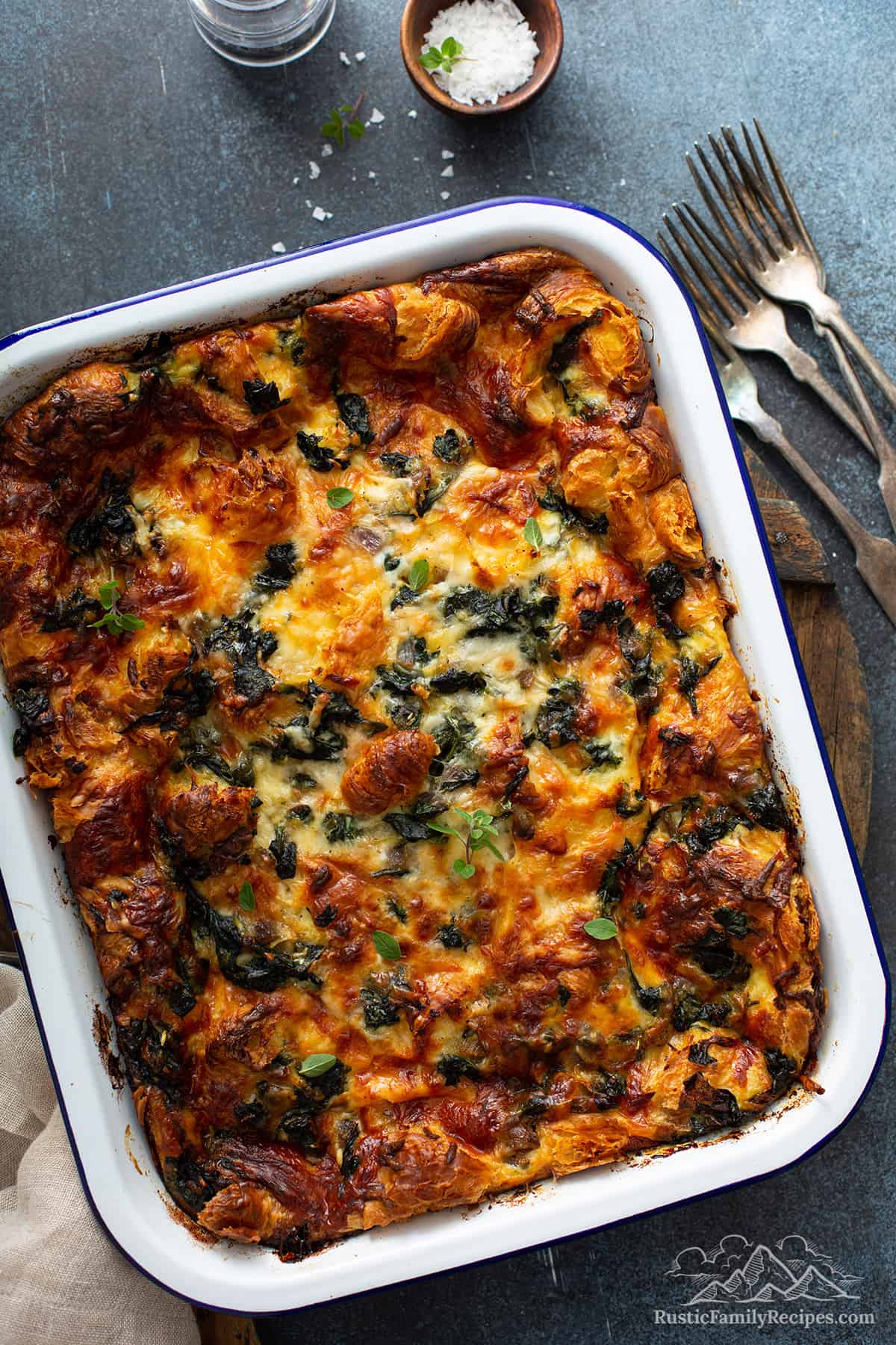 A cooked croissant strata in a white baking dish.