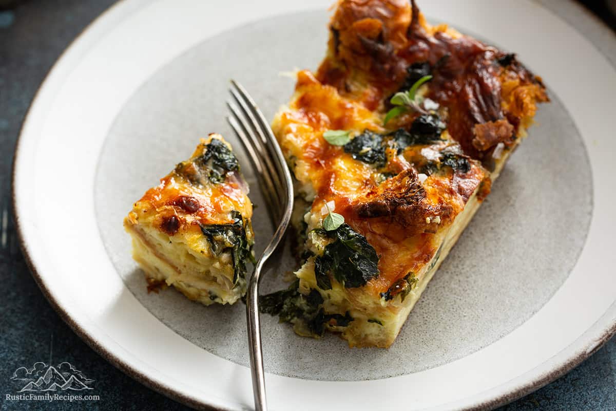 A slice of spinach strata on a while plate with a fork