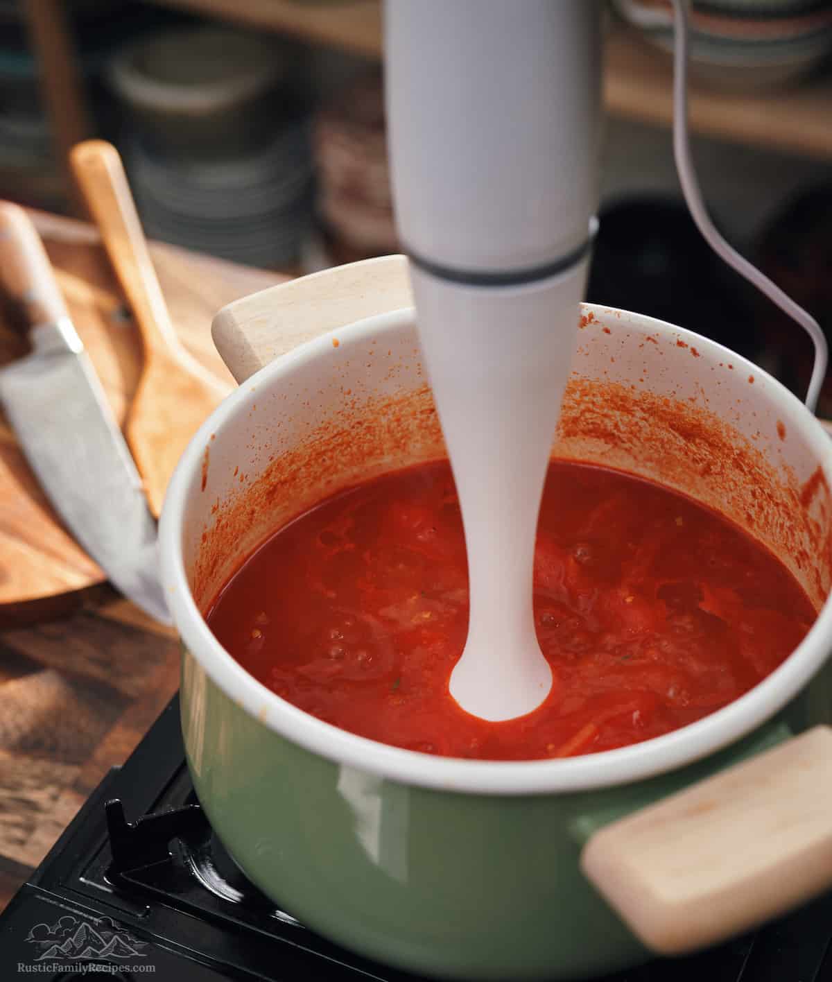 Immersion blender in a pot of tomato soup.