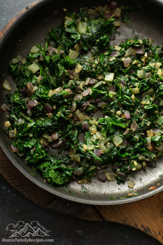 Onions and spinach cooking in a pan