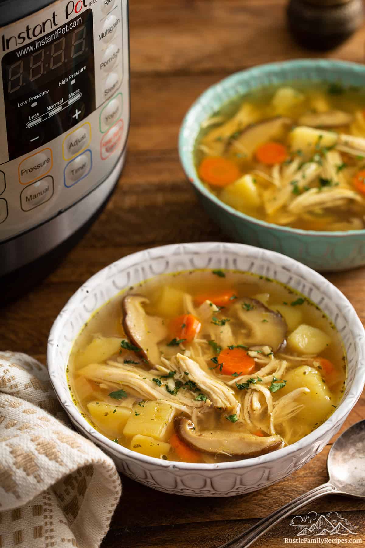 Two bowls of chicken soup in front of an Instant Pot