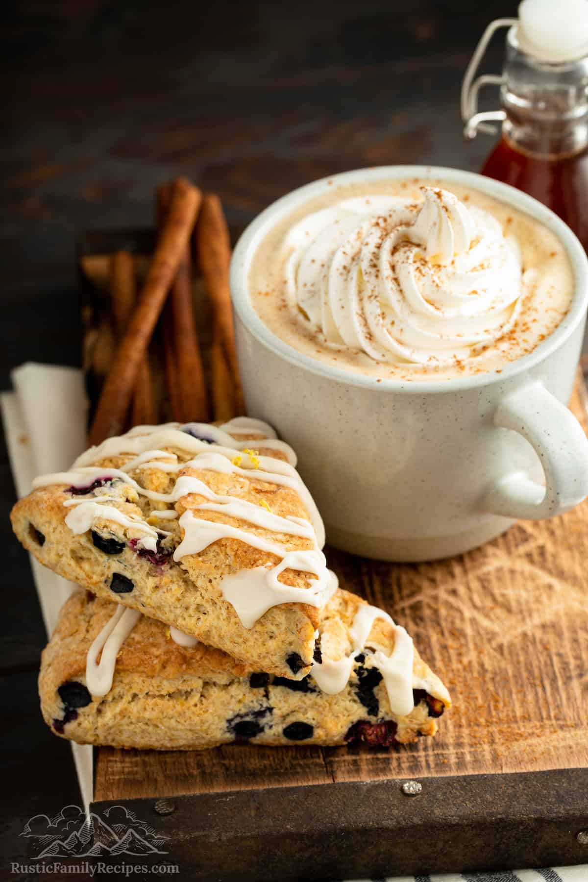 Two glazed blueberry scones stacked next to a Gingerbread Latte.
