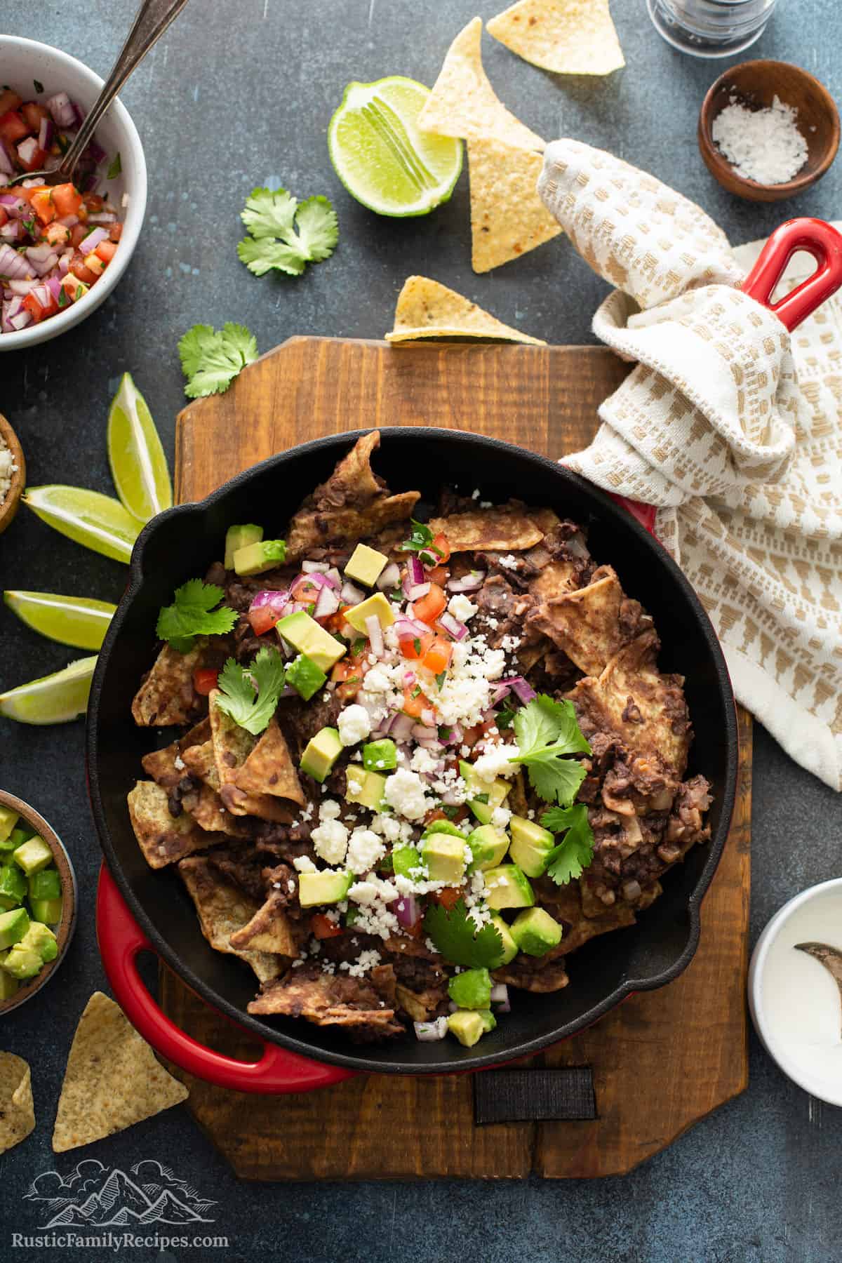 Black bean chilaquiles in a skillet topped with avocado, sour cream and salsa.