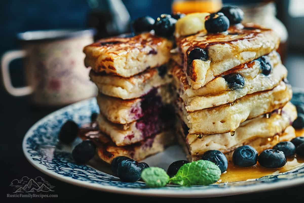 A stack of homemade pancakes with a wedge taken out to show the fluffy insides.