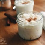 Two small mason jars with rice pudding garnished with cinnamon
