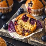 A sourdough blueberry muffin with a bite taken out next to other muffins.