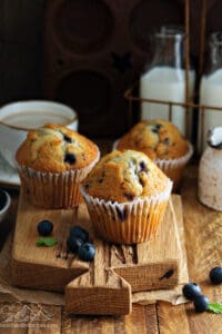 Three sourdough discard blueberry muffins on a wood board