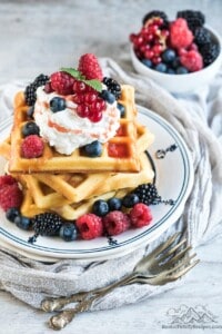 A stack of sourdough waffles topped with berries and whipped cream
