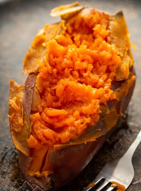 A baked sweet potato cut open next to a fork