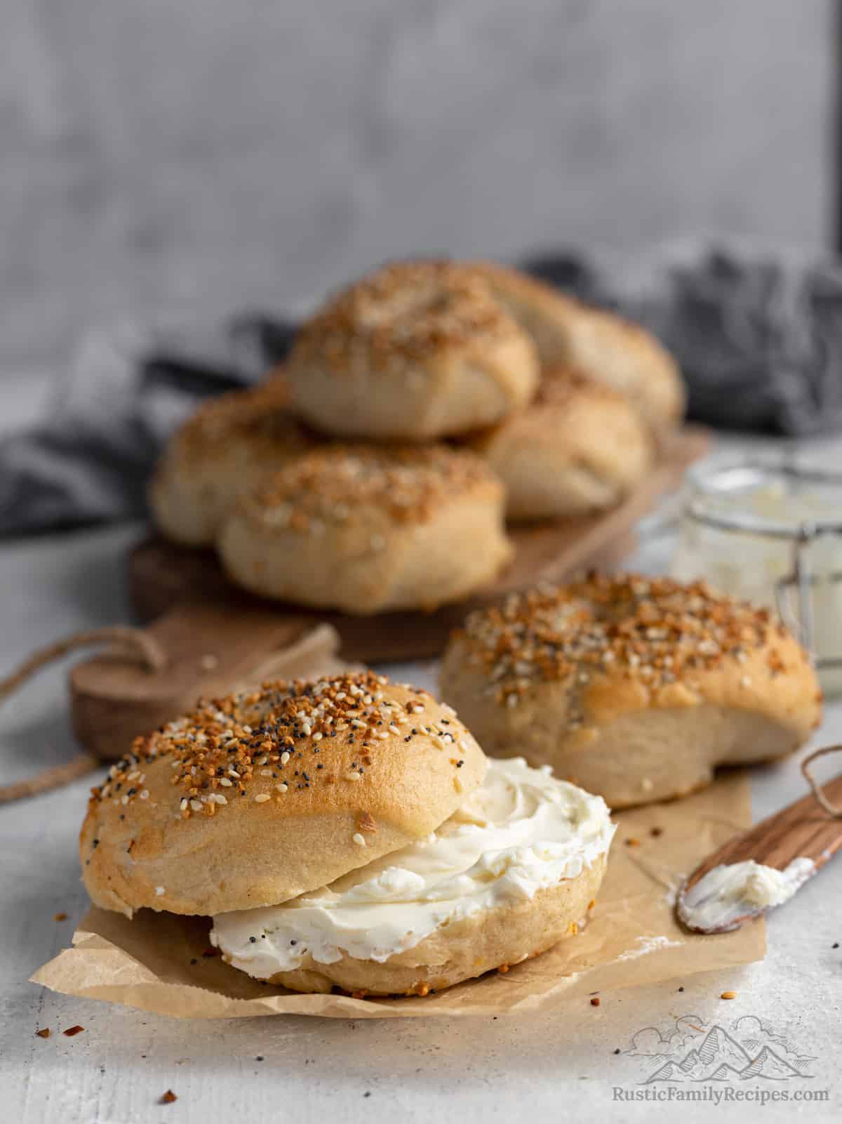 Homemade sourdough bagels, one cut open with cream cheese added.