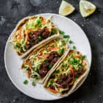 A white plate with three ground beef tacos