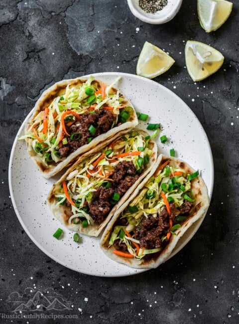 A white plate with three ground beef tacos