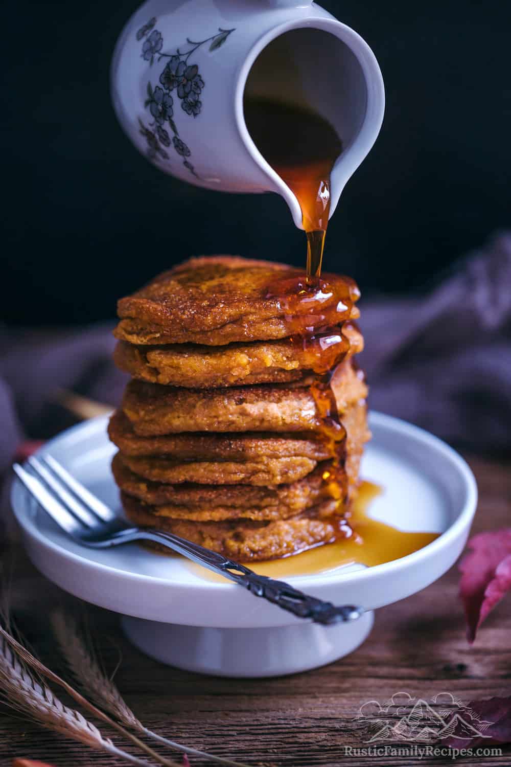 A stack of pumpkin pancakes with syrup being poured on top