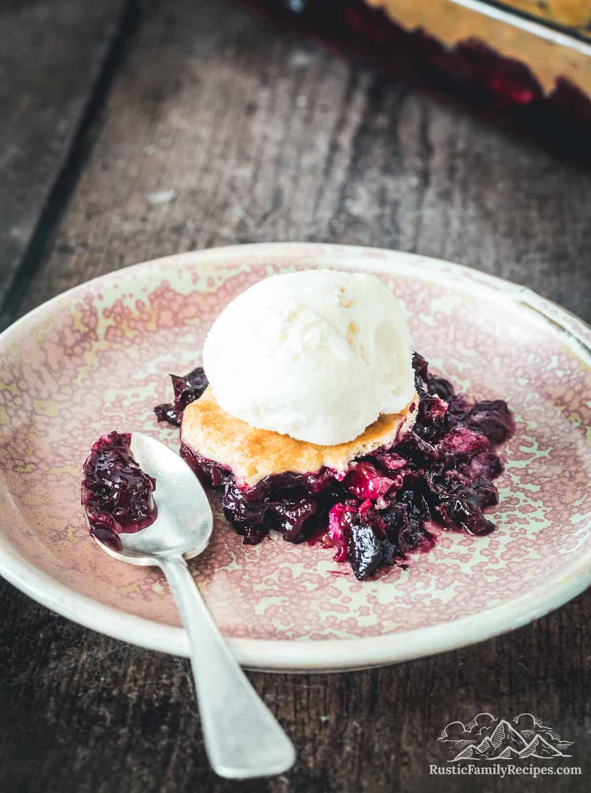 A serving of blueberry peach cobbler topped with ice cream
