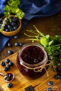 A jar on a wooden table with homemade blueberry sauce