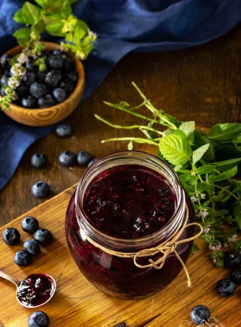 A jar on a wooden table with homemade blueberry sauce