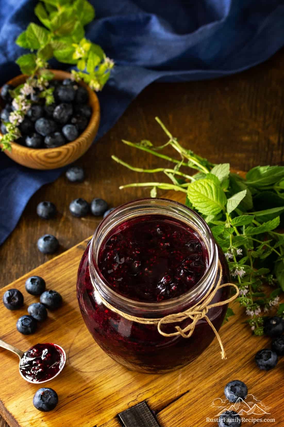 A jar on a wooden table with homemade blueberry sauce