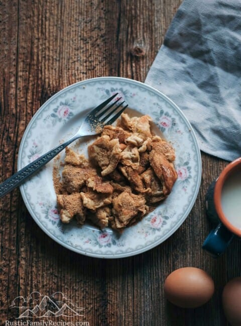 A rustic looking plate on a wooden counter with Kaiserschmarrn and a brown egg