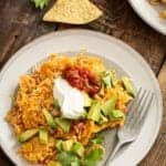 A plate of sweet potato migas topped with sour cream, salsa and avocado