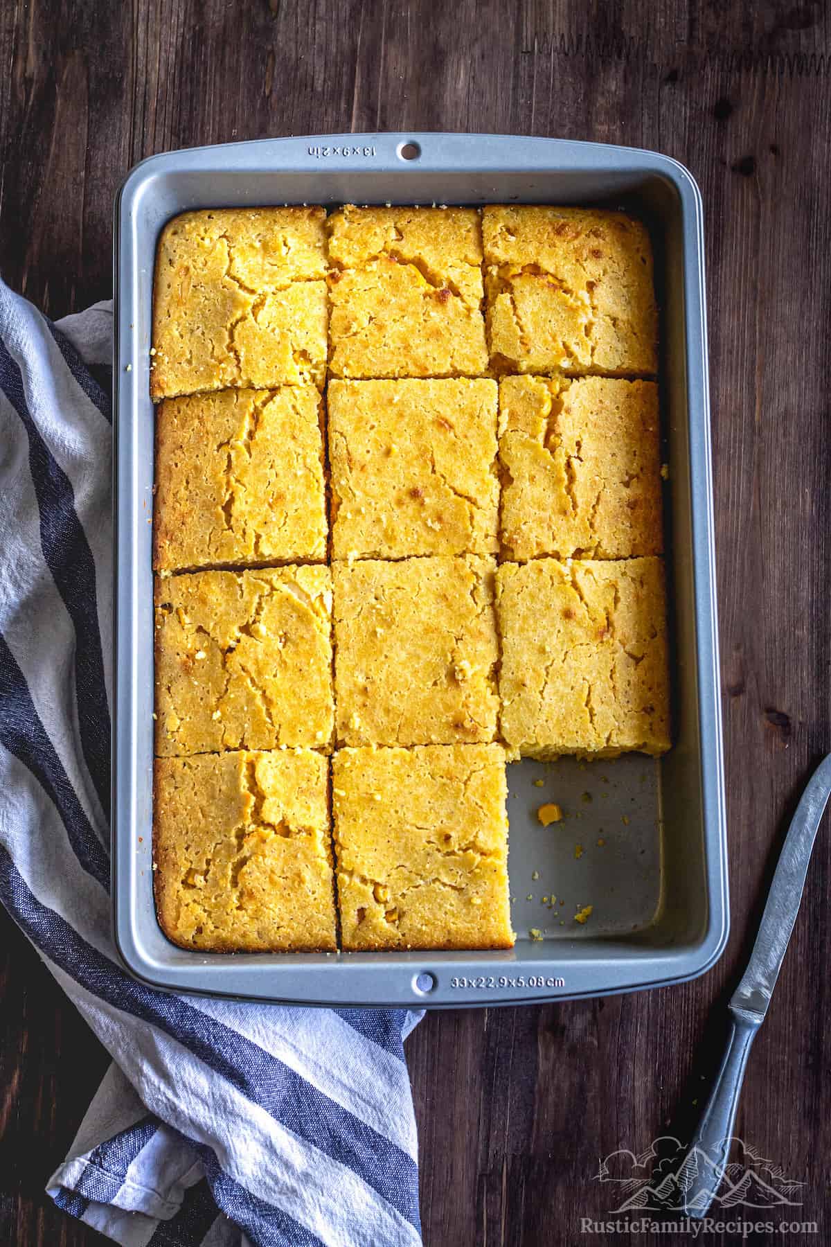Easy Cheddar Cornbread in a baking dish cut into 12 squares with one piece missing.