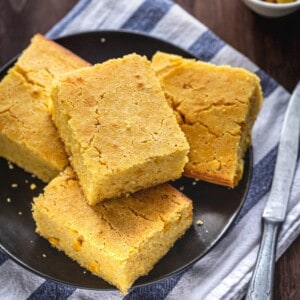Four pieces of Easy Cheddar Cornbread on a plate on top of a napkin with a knife.