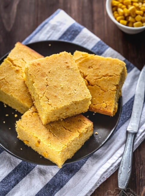 Four pieces of Easy Cheddar Cornbread on a plate on top of a napkin with a knife.