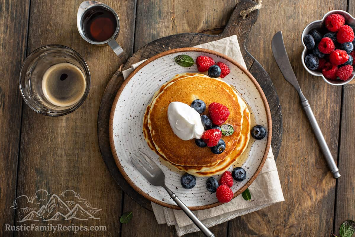 Aerial view of a stack of old fashioned pancakes topped with berries and whipped cream