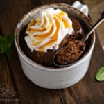 A nutella mug cake with a scoop taken out topped by whipped cream