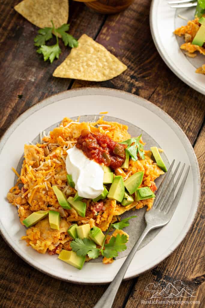A plate of sweet potato migas topped with sour cream, salsa and avocado