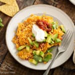 A plate of sweet potato migas topped with sour cream, salsa and avocado