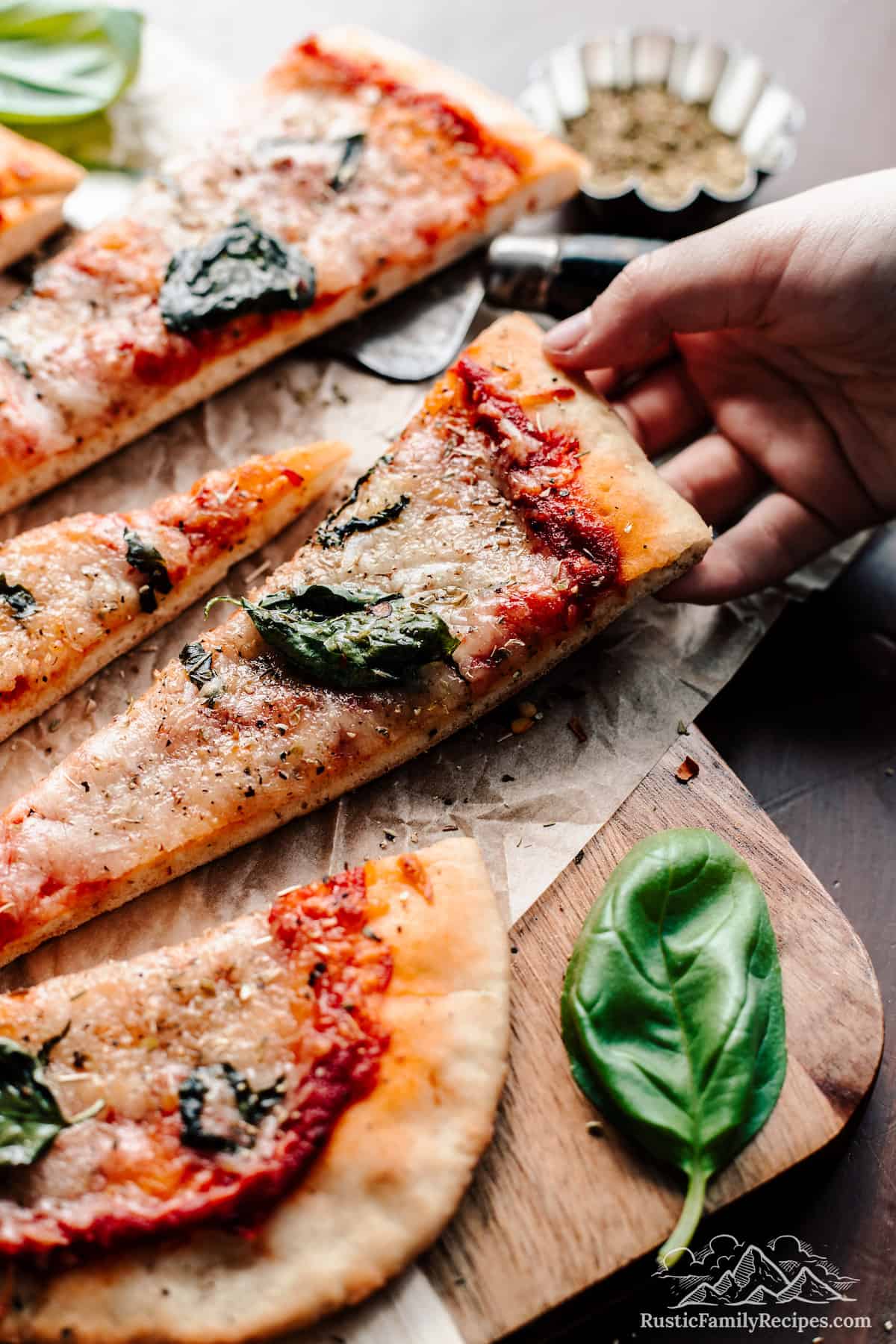 Slices of New York style sourdough pizza, a hand picking up a slice