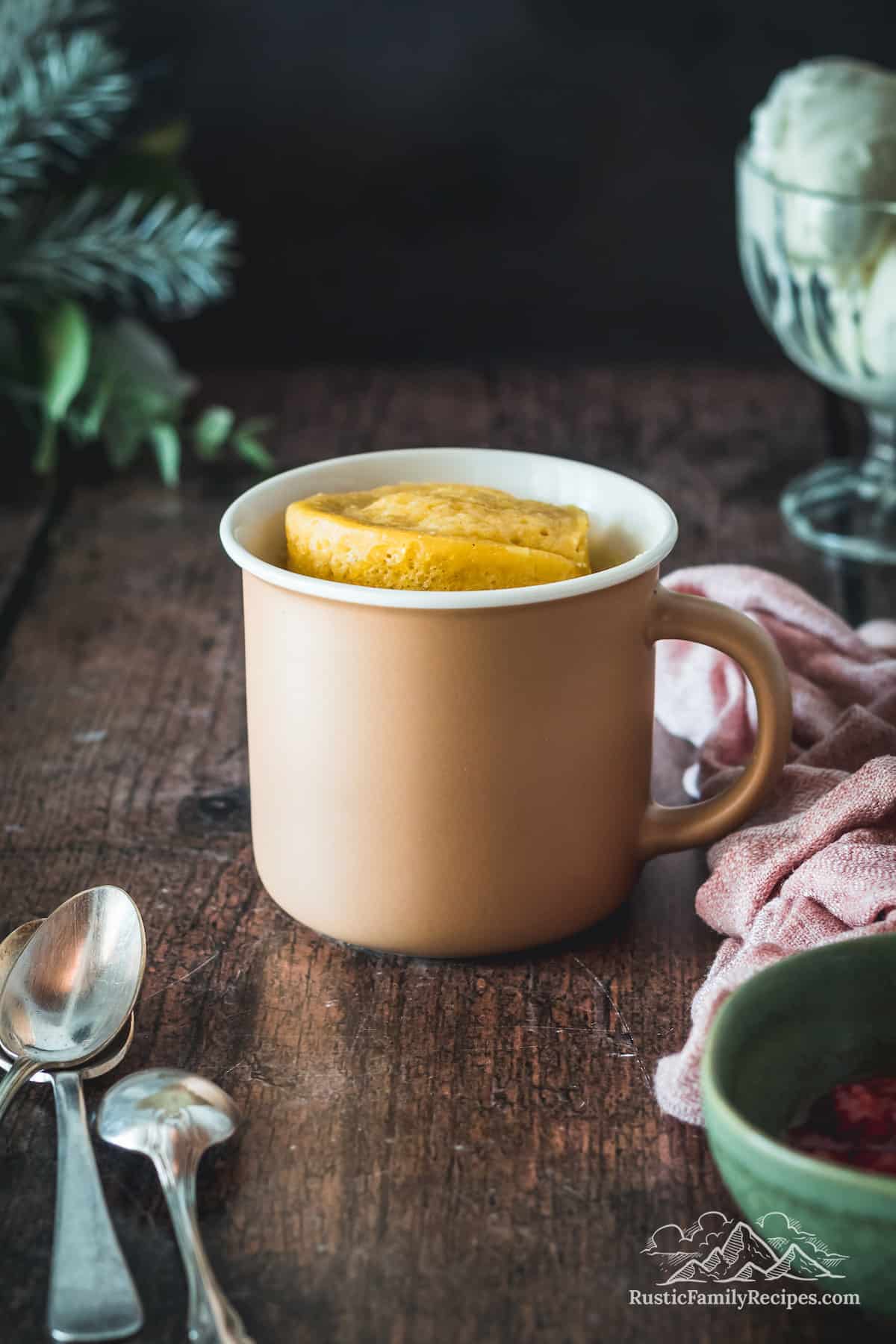 A vanilla buttermilk mug cake in a pink mug on a wood table
