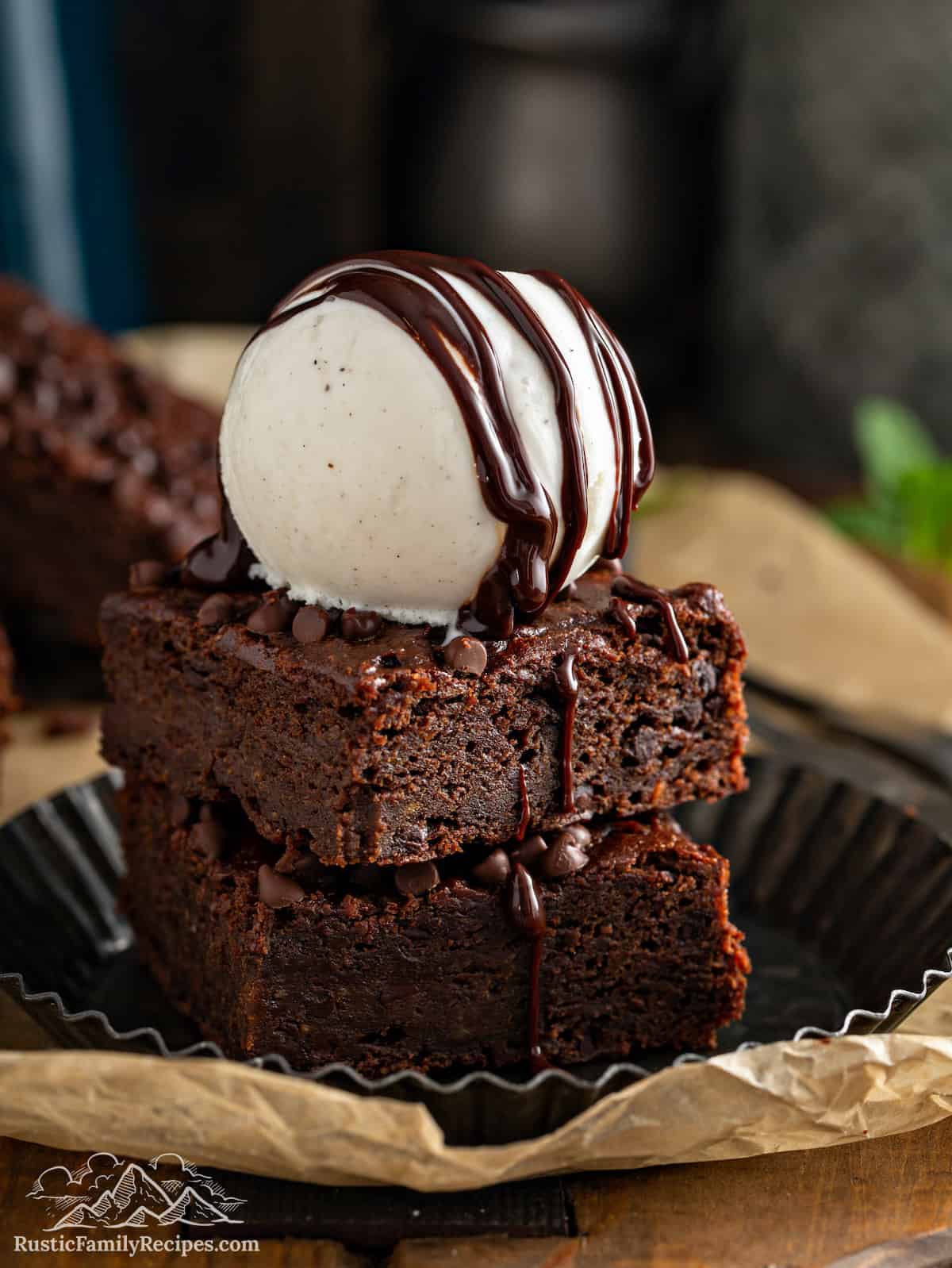 Two pumpkin sweet potato brownies stacked with vanilla ice cream on top